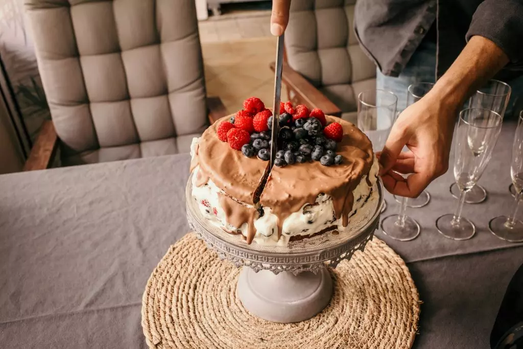 Fotoshooting 1. Geburtstag - Eine Frau h&auml;lt ein Messer und schneidet eine Geburtstagstorte zum 1. Geburtstag an.