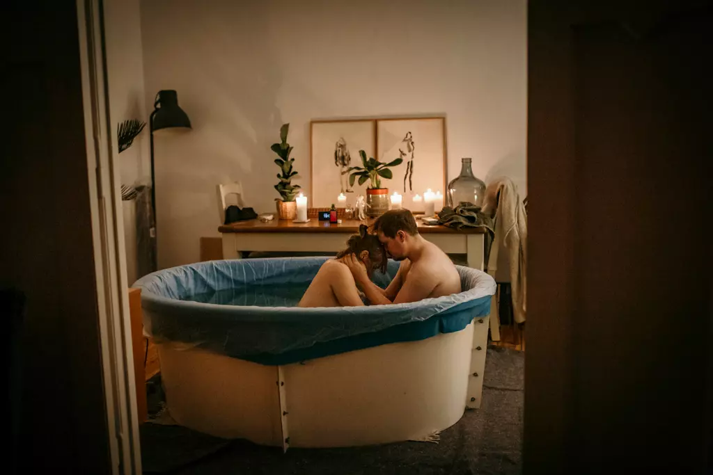 Geburtsreportage Berlin - Paar sitzt w&auml;hrend der Hausgeburt ihres Kindes im Pool.