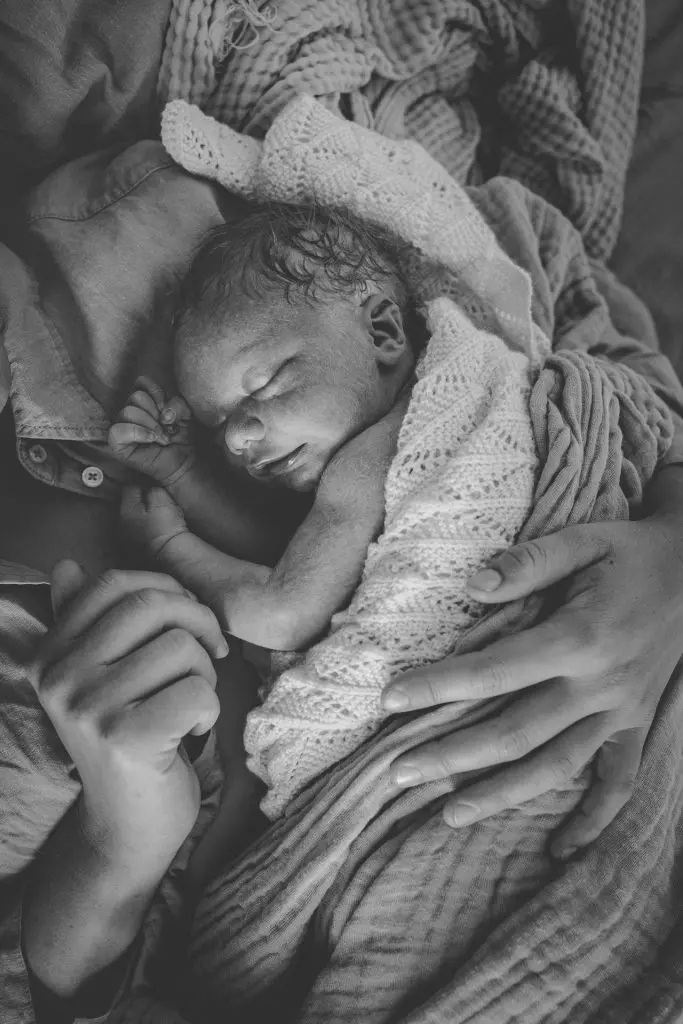 Neugeborenes Baby schl&auml;ft auf dem Oberk&ouml;rper der Mama in schwarz-wei&szlig;em Familienreportage-Foto