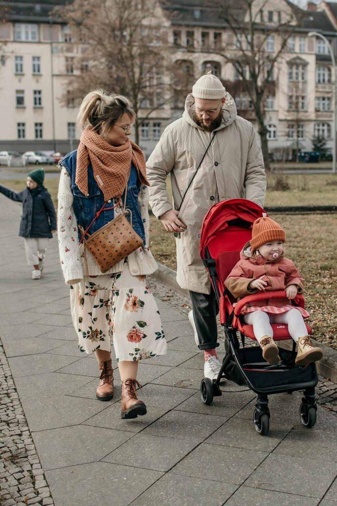 Familienreportage Berlin Treptow, Mama und Papa spazieren nebeneinander, Papa schiebt den Kinderwagen