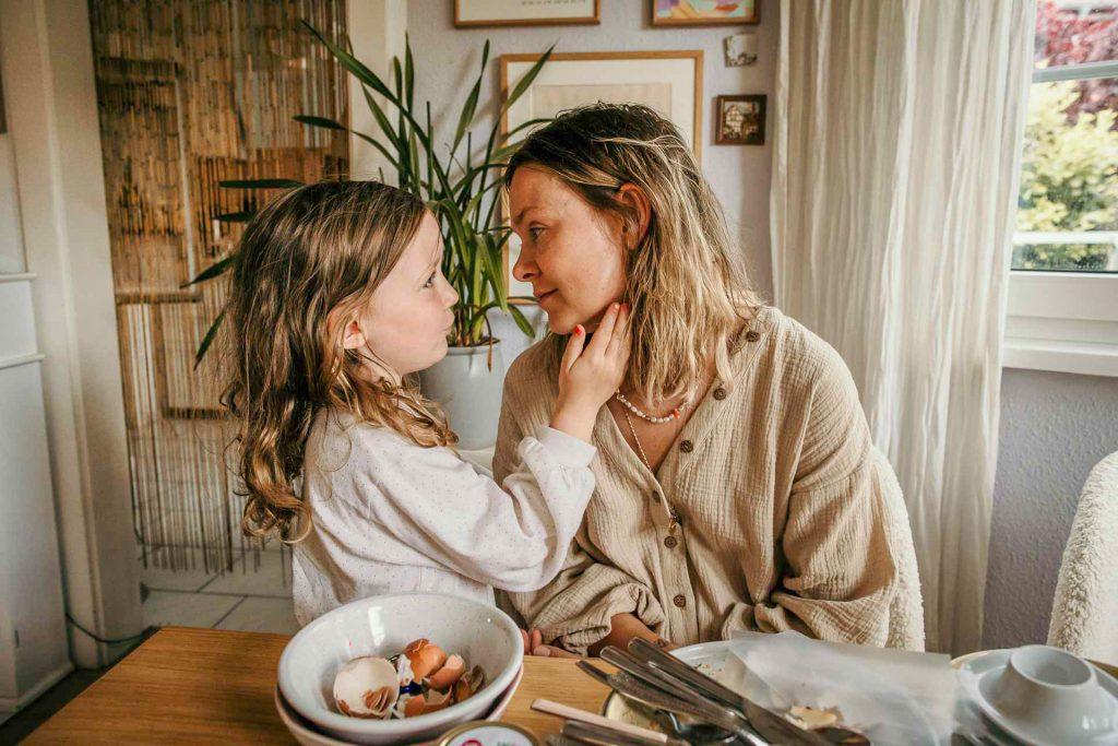 Familienfotoshooting Berlin, Tochter hat die Hand an Mamas Gesicht, beide schauen sich in die Augen