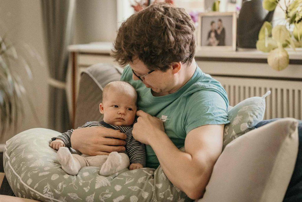 wochenbettfotografie berlin papa haelt baby couch wohnzimmer